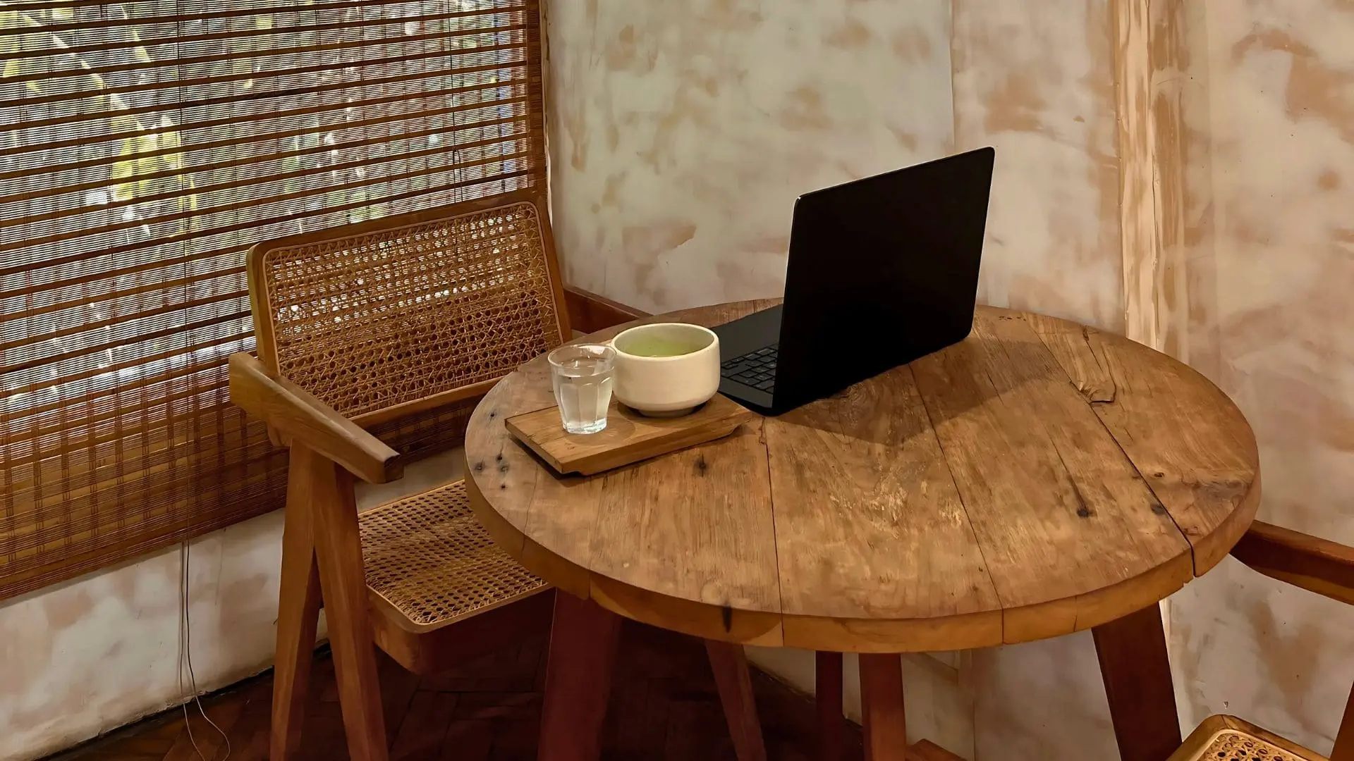 Mesa como escritoria con un portatil , café y agua en la mesa.