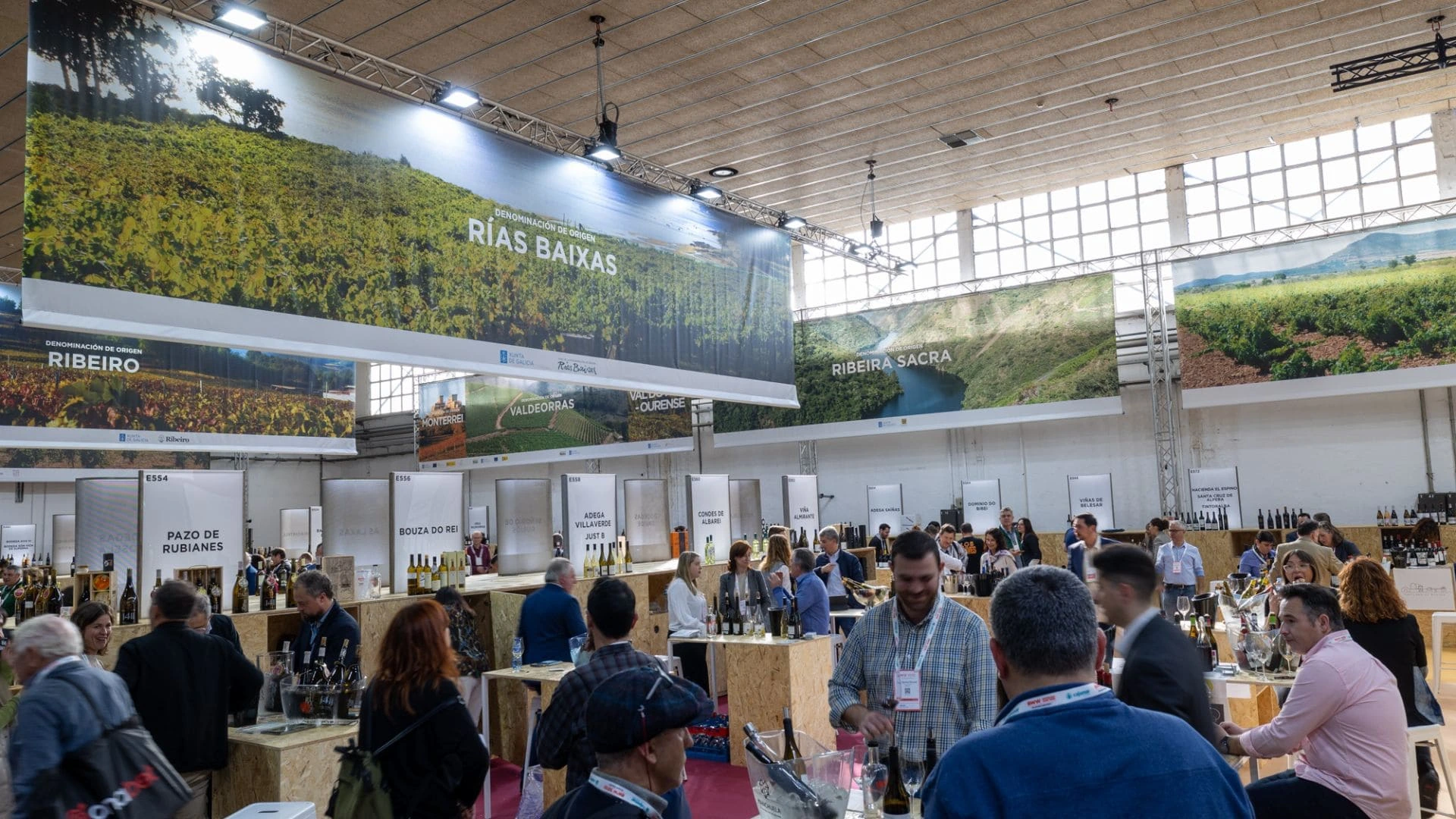 Feria de BCN Wine Week con carteles de rías baixas con personas bebeiendo vino