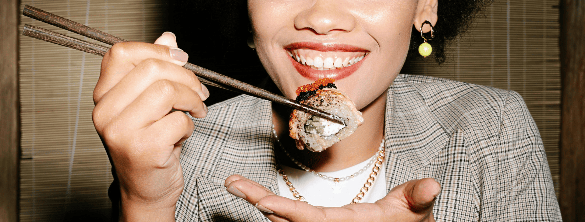 Chica sonriendo comiendo sushi con palillos